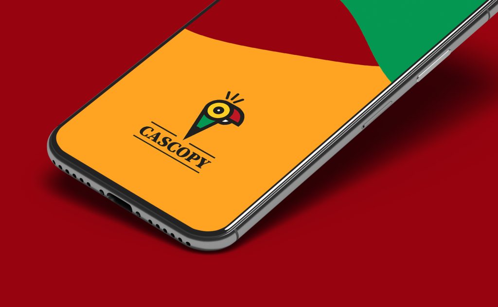 CAScopy logo with parrot, pencil, and speaker design displayed on a smartphone screen with a colorful background on a red surface.